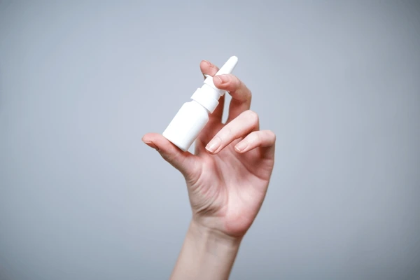 female-hand-holding-white-bottle-600nw-2711635481 — How to Use Nasal Spray Properly: A Post-Rhinoplasty Guide 2026